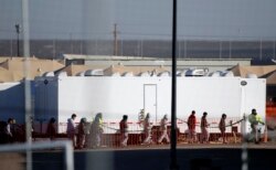 FILE - Migrant teens walk in a line through the Tornillo detention camp in Tornillo, Texas, Dec. 13, 2018. The Trump administration says it will keep the tent city holding more than 2,000 migrant teenagers open through early 2019.