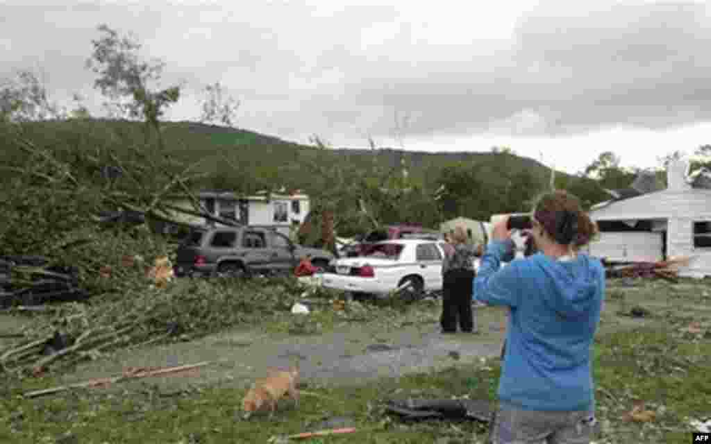 Angela Milchak uses a cell phone to photograph damage to her house and cars from fallen trees after a Wednesday, April 27, 2011 storm system battered the Tiftonia neighborhood of Chattanooga, Tenn.