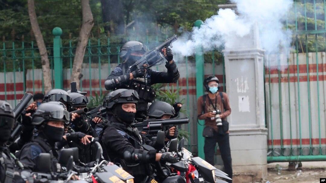 Seorang polisi menembakkan gas air mata untuk membubarkan demo menolak UU Cipta Karya yang disahkan pekan lalu, di Jakarta, Selasa, 13 Oktober 2020. 