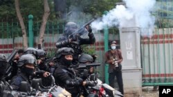 Seorang polisi menembakkan gas air mata untuk membubarkan demo menolak UU Cipta Karya yang disahkan pekan lalu, di Jakarta, Selasa, 13 Oktober 2020. 