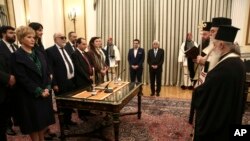 Greece Cabinet Reshuffle: Newly appointed ministers and deputy ministers take an oath as Greek President Prokopis Pavlopoulos, center right, and Prime Minister Alexis Tsipras, center left, look on, during a swearing in ceremony at the Presidential palace in Athens , Saturday, Oct. 5, 2016. 