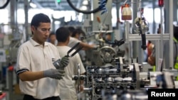 FILE - Employees work on an assembly line at the General Motors Powertrain-Uzbekistan plant in Tashkent, Aug. 31, 2012.