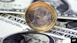 FILE - A euro coin sits atop US one-dollar notes in Gelsenkirchen, Germany. 