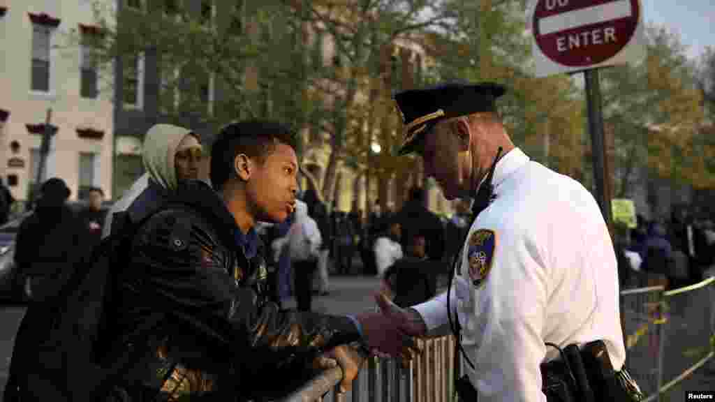 Un adolescent, Tremaine Holmes, s’échange une poignée de main avec le capitaine Erik Pecha en face de la station de police de district de Baltimore lors d'une manifestation contre la mort en garde à vue de Freddie Gray à Baltimore, le 23 avril 2015.