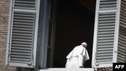 FILE - Pope Francis leaves after turning away from the window of the apostolic palace overlooking an empty Saint Peter's square after delivering his Angelus prayer at the Vatican, March 22, 2020.