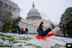 FILE - Silvestre, 6, of Washington, sleds over a snow bump on the hill at the U.S. Capitol, as schools are closed due to a winter storm, Tuesday, Jan. 16, 2024. (AP Photo/Jacquelyn Martin)