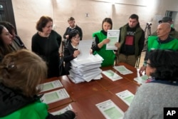 Members of an election commission count ballots at a polling station after the parliamentary election in Tbilisi, Georgia, Oct. 26, 2024.