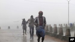 People run for shelter as heavy rain and wind gusts rip through the Bay of Bengal coast at Gopalpur, Orissa, about 285 kilometers (178 miles) north east of Visakhapatnam, India, Sunday, Oct. 12, 2014. 