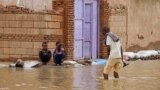 A man wades through a flooded street in the town of Shaqilab, about 25 kilometers southwest of the capital, Khartoum, Sudan, Aug. 31, 2020.