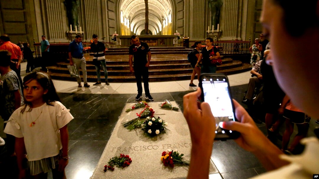 FILE - People stand around the tomb of late Spanish dictator Francisco Franco, inside the basilica at the Valley of the Fallen monument, near El Escorial, outside Madrid, Spain, Aug. 24, 2018. 