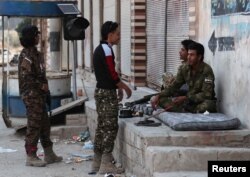 Turkey-backed Syrian rebel fighters chat in the border town of Tal Abyad, Syria, Oct. 18, 2019.