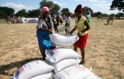 FILE: Villagers queue to collect their monthly food aid ration of cereals at a school in drought hit Masvingo, Zimbabwe.