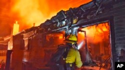 En esta foto del viernes, 6 de julio de 2018, proporcionada por el Departamento de Bomberos del Condado de Santa Bárbara, un bombero lanza agua a una vivienda cerca de Fairview Ave., en Goleta, California. (Mike Eliason / Departamento de Bomberos del Condado de Santa Bárbara vía AP)