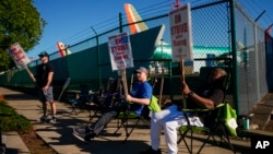 FILE - Boeing 737 Max aircrafts are seen behind fences as striking Boeing workers picket on Sept. 24, 2024, next to the company's facilities in Renton, Washington. Analysts say strikes and two hurricanes kept employers from adding many jobs in October.