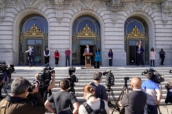 San Francisco health director Dr. Grant Colfax talks about the first confirmed case of the omicron variant as Mayor London Breed, right of podium, listens during a COVID-19 briefing outside City Hall in San Francisco, California, Dec. 1, 2021.