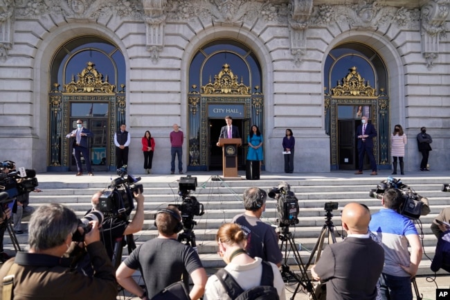 San Francisco health director Dr. Grant Colfax talks about the first confirmed case of the omicron variant as Mayor London Breed, right of podium, listens during a COVID-19 briefing outside City Hall in San Francisco, California, Dec. 1, 2021.