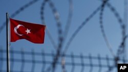 FILE - A Turkish flag is seen fluttering behind a barbed wire fence.