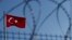 FILE - A Turkish flag is seen fluttering behind a barbed wire fence.