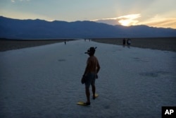 FILE - Marko Leszczuk walks along the salt flats at Badwater Basin as the sun sets, Sunday, July 16, 2023, in Death Valley National Park, Calif. (AP Photo/John Locher)