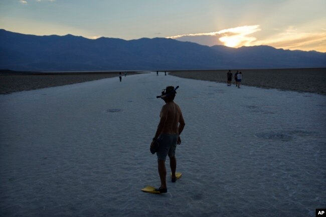 FILE - Marko Leszczuk walks along the salt flats at Badwater Basin as the sun sets, Sunday, July 16, 2023, in Death Valley National Park, Calif. (AP Photo/John Locher)