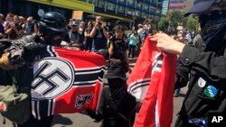Counterprotesters tear a Nazi flag, Aug. 4, 2018 in Portland, Ore. Small scuffles broke out as police dispersed hundreds of right-wing and self-described anti-fascist protesters.