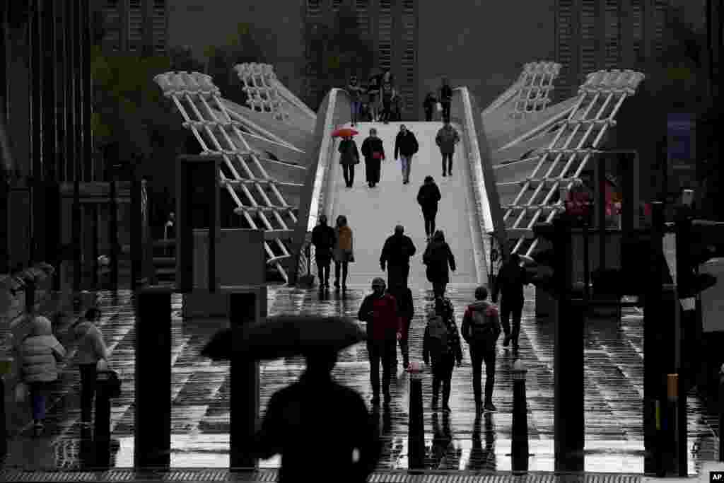 People walk across the London Millennium Footbridge.