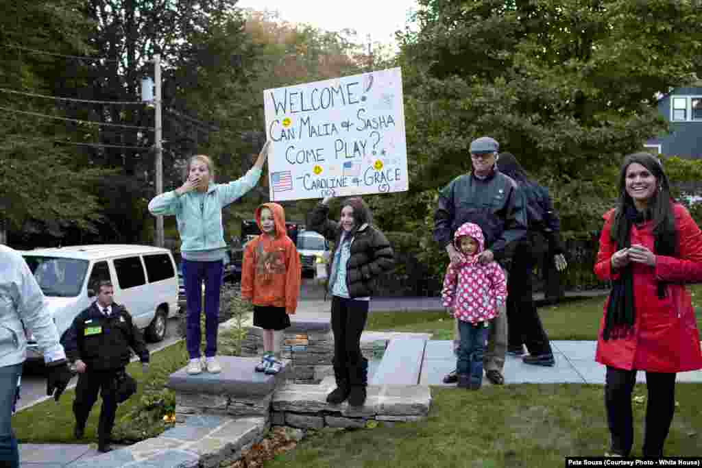 Des jeunes filles attendent avec des pancartes demandant si elles peuvent jouer avec les filles du président Obama, à Newton, le 16 octobre 2010. (White House/Pete Souza)