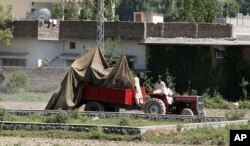 This May 2, 2011 file photo shows a tractor trolley carrying the wreckage of a helicopter that crashed next to the wall of Osama bin Laden's compound, Abbottabad, Pakistan. (AP)