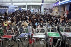 Protesters use luggage trolleys to block the walkway to the departure gates during a demonstration at the Airport in Hong Kong, Aug. 13, 2019.