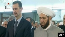 Gambar dari televisi Suriah menampilkan Presiden Bashar al-Assad (kiri) melangsungkan sholat Idul FItri di Damaskus (8/8).