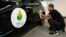 FILE - An employee installs a sticker which reads 100% electric next to the logo of the upcoming COP21 Climate Change Conference on a Nissan LEAF electric car in Boulogne-Billancourt, near Paris, France, November 16, 2015.
