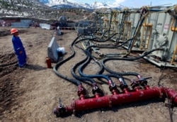 FILE - A worker helps monitor water pumping pressure and temperature at an oil and natural gas extraction site in Colorado, March 29, 2013.