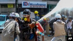 Anti-coup protesters discharge fire extinguishers to counter the impact of the tear gas fired by police during a demonstration in Yangon, Myanmar Thursday, March 4, 2021. (AP Photo)