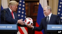 Presiden AS Donald Trump menerima bola dari Presiden Rusia Vladimir Putin dalam jumpa pers bersama usai pertemuan mereka di Helsinki, Finlandia, Senin (16/7). 