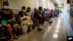 FILE - People queue to get vaccinated against COVID-19, at Lenasia South Hospital, near Johannesburg, South Africa, Dec. 1, 2021.