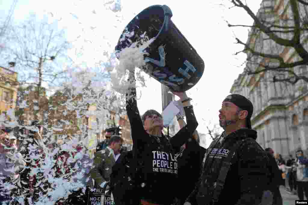 A woman throws feathers during an anti-vaccine protest, on the COVID-19 Day of Reflection, marking 5 years since the start of the pandemic, in London.