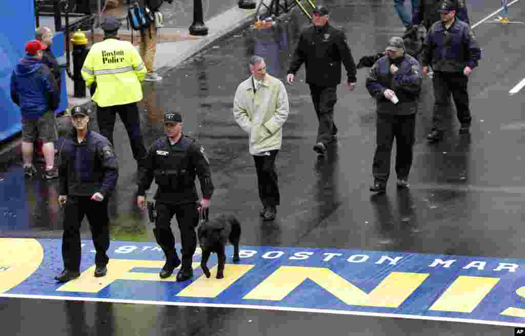 Security personnel walk across the Boston Marathon finish line prior to a remembrance ceremony for family members and survivors of the 2013 Boston Marathon bombing, on Boylston Street, April 15, 2014.