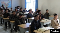 FILE - Uyghur men attend a lesson in a school in Yining, China's Xinjiang province, October 13, 2005.