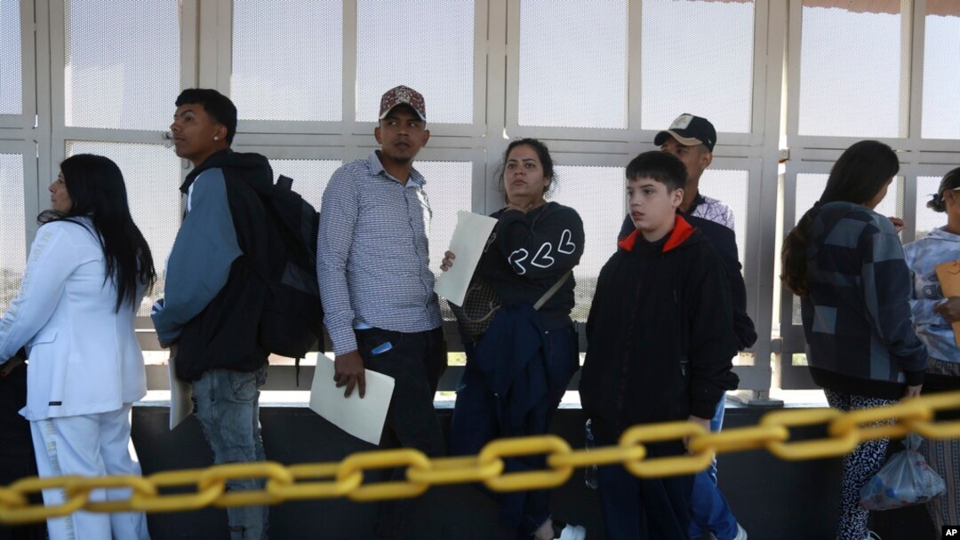Migrants wait in line for US agents to examine their documents requesting an appointment to apply for asylum, at the Paso del Norte international bridge, in Ciudad Juarez, Mexico, Nov. 1, 2024. 