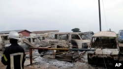 Un pompier se tient près des véhicules incendiés lors d’une évasion à la prison centrale de Makala à Kinshasa, RDC, 17 mai 2017.