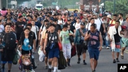 Migrantes caminan por la carretera que atraviesa Suchiate, estado de Chiapas, en el sur de México, el domingo 21 de julio de 2024, al emprender su viaje hacia a la frontera con Estados Unidos. 