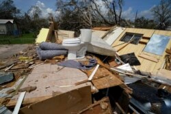FILE - Remnants of the half-destroyed mobile home of James Townley, who is living in the standing half, are seen in Lake Charles, La., in the aftermath of Hurricane Laura, Aug. 30, 2020.