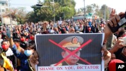 Seorang pengunjuk rasa memegang spanduk bergambar Panglima Tertinggi militer Myanmar Jenderal Min Aung Hlaing saat protes di Mandalay, Myanmar, Selasa, 9 Februari 2021. (Foto: AP)