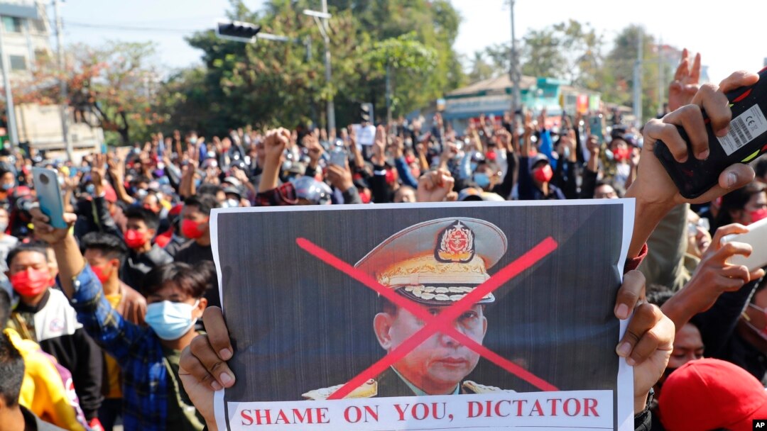 Seorang pengunjuk rasa memegang spanduk bergambar Panglima Tertinggi militer Myanmar Jenderal Min Aung Hlaing saat protes di Mandalay, Myanmar, Selasa, 9 Februari 2021. (Foto: AP)