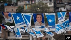Banners with a portrait of Honduran President and current presidential candidate Juan Orlando Hernandez hang outside a polling station during the general elections in Tegucigalpa, Nov. 26, 2017.