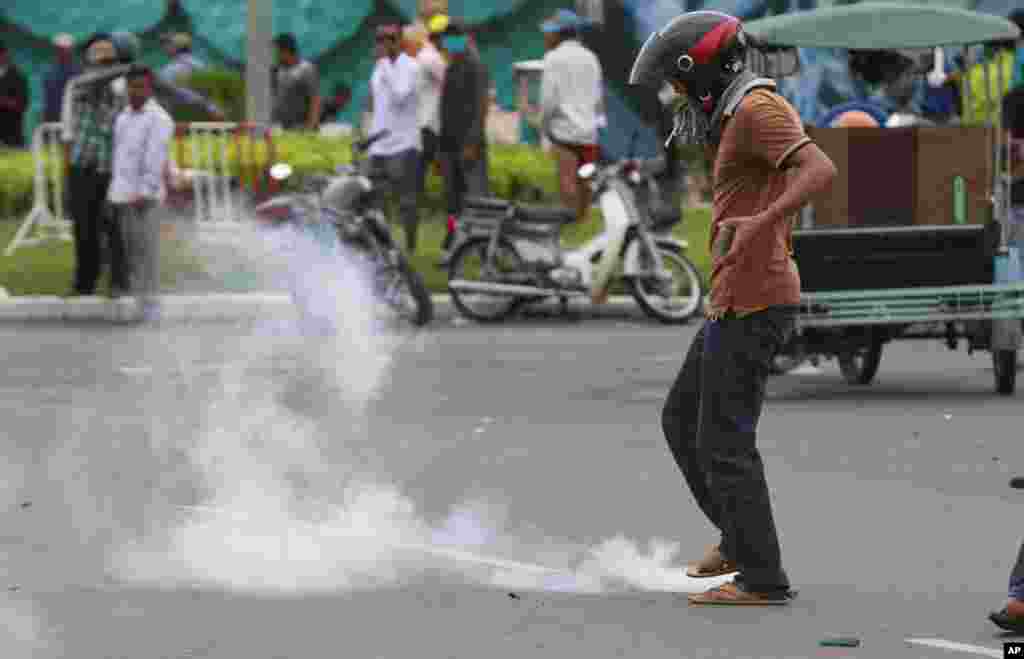 A supporter of Cambodia's opposition party avoids a smoke grenade near the Royal Palace in Phnom Penh, Sept. 15, 2013