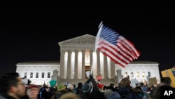 FILE - a protester waves an American flag in front of the Supreme Court during a protest about President Donald Trump's recent executive orders in Washington. 