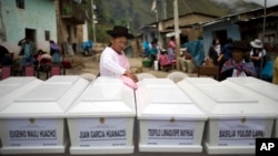 In this March 29, 2016 photo, a woman dusts coffins holding the remains of villagers who were slain more than two decades ago by Shining Path rebels, before a group burial service in Ccano, a village in the Huanta area of Ayachcuo department, Peru. In Ccano, many peasants worked with the military to fight the rebels, and the Shining Path stormed a church here in retaliation, killing everyone praying inside in 1991.