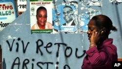 A Haitian woman uses her mobile phone next to a poster of Haiti's presidential candidates Mirlande Manigat in Port-au-Prince, March 18, 2011