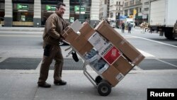 FILE - UPS delivery man pushes a trolley of packages in New York, Dec. 27, 2013.